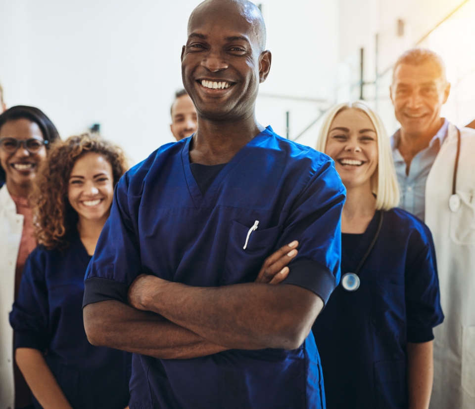 a diverse group of health professionals in scrubs facing the camera and smiling