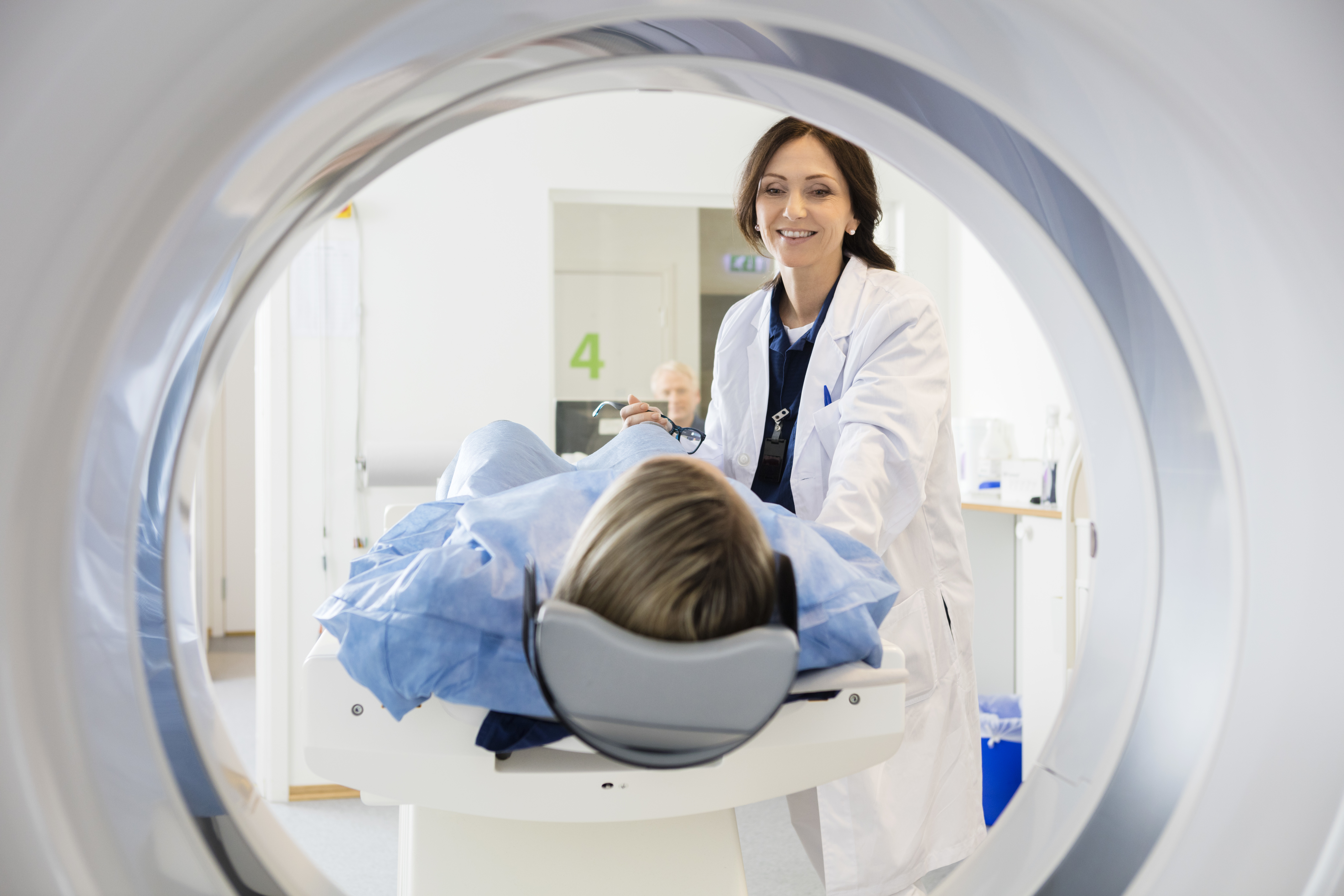 doctor looking at patient undergoing ct scan