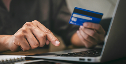 focus on the hands of a person using a laptop to input their credit card number while holding up the card