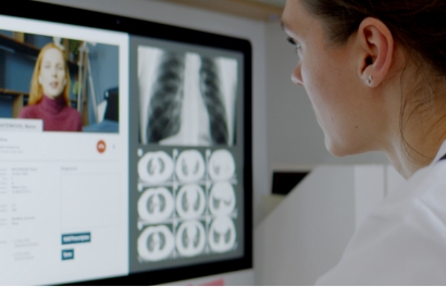 a woman faces away from the camera, looking at medical information on a computer monitor