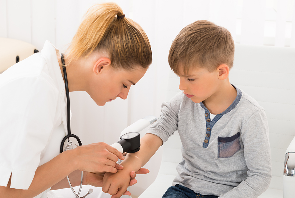 dermatologist examining boy's skin